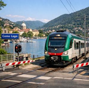 a green and white train on tracks next to a body of water at Grazioso Bilocale della Rosa a Cadorago in Fino Mornasco