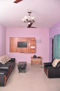 ein Wohnzimmer mit einem Sofa und einem TV in der Unterkunft Srirangam Service Apartment in Tiruchchirāppalli