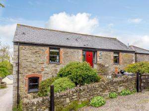 a stone house with a red door and a stone wall at 2 Bed in Fowey oc-55383 in Golant