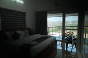 a bedroom with a bed and a balcony with a view at Samudra Retreats Vagamon in Vagamon +25 photos
