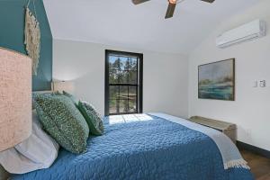 a bedroom with a bed with a blue comforter and a window at Terlingua at the Bend in Wimberley
