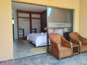 a bedroom with a bed and two chairs and a mirror at Vakasha Lodge in Siphofaneni +69 photos
