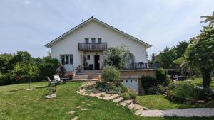 a white house with a balcony and a yard at La Maison in Mirebeau-sur-Bèze