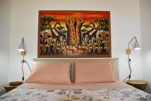 a bedroom with a painting above a bed with pink pillows at La Casetta di Saha in collina in Itri