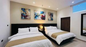 two beds in a room with paintings on the wall at Hotel Murahno Collection in Cúcuta