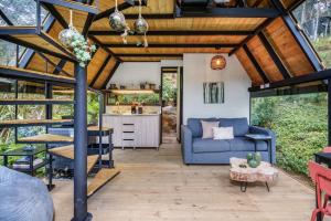a living room with a blue couch and a kitchen at Glamping en El Retiro in El Retiro