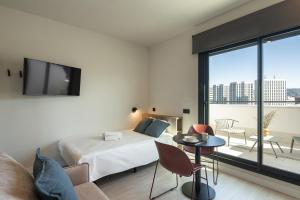 a bedroom with a bed and a living room with a balcony at Codomo Living Granada in Granada