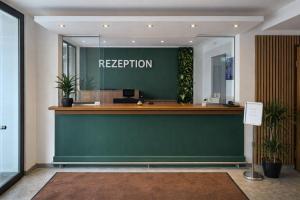 a reception desk in an office with a green wall at Hotel B1 in Berlin