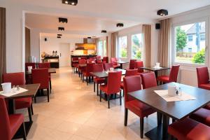 a dining room with tables and red chairs at Hotel B1 in Berlin