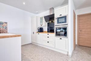 a white kitchen with white cabinets and a microwave at BELLEVUE 2, piscine, jacuzzi, sauna in Champcevinel
