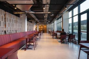 a restaurant with red benches and tables and windows at Codomo Living Granada in Granada