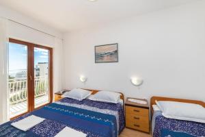 two beds in a room with a window at Apartments Palmero in Gradac