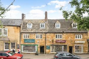 an old brick building with cars parked in front of it at Redesdale View, High Street with Private Garden in Moreton in Marsh