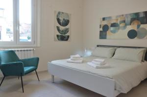 a white bedroom with a bed and a blue chair at DomuS Miniato in San Miniato