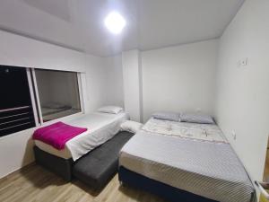 two beds in a small room with a window at Apartahotel y casa de campo AMARU in San Gil
