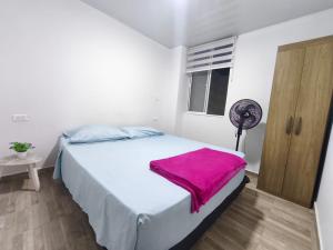 a bedroom with a bed with a pink blanket on it at Apartahotel y casa de campo AMARU in San Gil