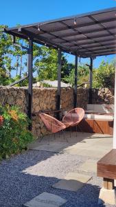 a patio with two chairs and a table and a stone wall at 바티하우스 in Ara-ri