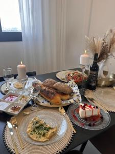 a table topped with plates of food and candles at Sunset Home - Netanya Roof & Sea View in Netanya
