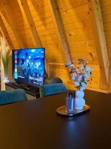 a table with a vase of flowers and a tv at Vikendica Sofijina Luka in Slatina Varoš