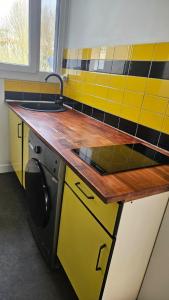 a kitchen with yellow and black cabinets and a sink at T3 idéalement situé in Mérignac