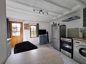 a kitchen with a table and a stove and refrigerator at La Champêtre in Beaumesnil