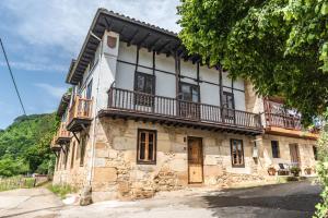 an old stone house with a balcony on a street at La Villa de Carla in Borleña