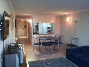 a living room with a table and a kitchen at Departamento Playa Amarilla Con Con in Concón