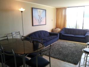 a living room with a blue couch and a glass table at Departamento Playa Amarilla Con Con in Concón +8 photos