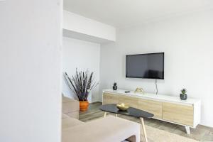 a living room with a tv on a white wall at A Quintinha by YOUR KEY MADEIRA in Santa Cruz