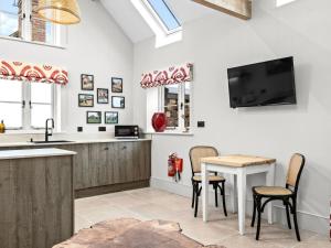 a kitchen with a table and a tv on the wall at 1 Bed in Ludlow oc-92768 in Hopton Cangeford +6 photos