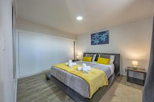 a bedroom with a large bed with yellow pillows at A Quintinha by YOUR KEY MADEIRA in Santa Cruz