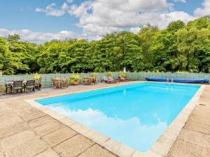 a swimming pool with tables and chairs next to a fence at 2 Bed in Saltash oc-88309 in Wotter