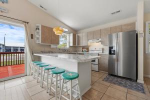 a kitchen with a counter with stools and a refrigerator at 5085 - Knapp's at the Beach in Kill Devil Hills +46 photos