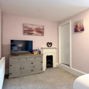 a living room with a television and a fireplace at The Cleave Inn in Lustleigh +28 photos