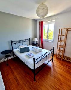 a bedroom with a bed with a wooden floor and a window at Villa SURF Situation exceptionnelle à 3 min à pied de la plage de Pors Carn Pour 5 personnes Authentique Bien équipée Jardin & BBQ Parking privatif in Penmarch