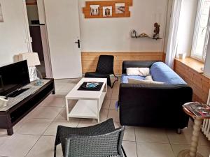 a living room with a blue couch and chairs at Villa SURF Situation exceptionnelle à 3 min à pied de la plage de Pors Carn Pour 5 personnes Authentique Bien équipée Jardin & BBQ Parking privatif in Penmarch