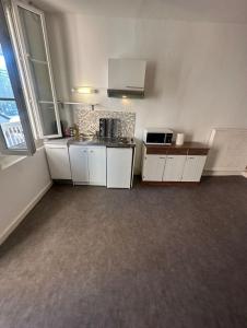 a small kitchen with white cabinets and a microwave at Dortoir Entier Privatif in Tarbes