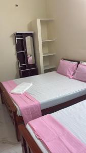 two beds in a room with pink and white sheets at Bhuvanavasigal alayam in Tiruvannāmalai