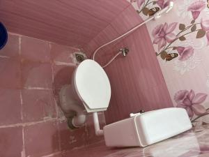 a white toilet in a bathroom with flowers on the wall at Bhuvanavasigal alayam in Tiruvannāmalai +22 photos