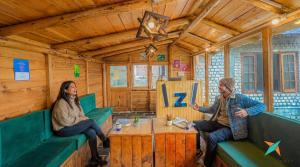 a man and woman sitting in a room in a train cabin at Zostel Homes Khajjiar in Chamba +27 photos