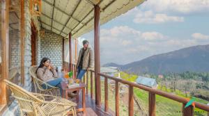 a man and woman sitting on a porch of a house at Zostel Homes Khajjiar in Chamba