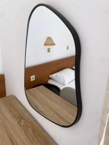 ein Spiegel an der Wand neben einem Bett in der Unterkunft Pasiphae Self Hotel in Heraklion + 3 Fotos