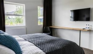 a bedroom with a bed and a flat screen tv at Litli Geysir Hotel in Haukadalur