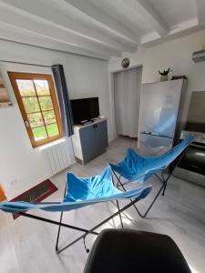 a living room with two blue chairs and a refrigerator at La Champêtre in Beaumesnil