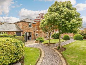 a garden with a tree and a house at 3 Bed in Driffield oc-92697 in Lund