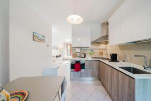 a large kitchen with white cabinets and a sink at Villetta Le Scaje in Torri del Benaco