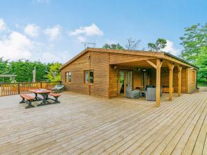 a wooden cabin with a deck with a table at 2 Bed in Malton oc-87936 in West Heslerton
