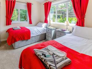 two beds in a bedroom with red curtains at 2 Bed in Malton oc-87936 in West Heslerton