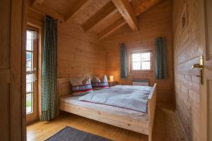 ein Schlafzimmer mit einem Bett in einer Holzhütte in der Unterkunft Pfenniggeiger-Hütte in Philippsreut