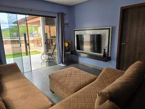 a living room with a couch and a tv at Casa Parque do Ribeirão - Casa com piscina in Lençóis